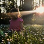Person sitting quietly in the daisies reflecting on learning to trust yourself