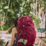 Woman carrying a heavy backpack representing the cost of wearing your armour and carrying protective patterns through life.