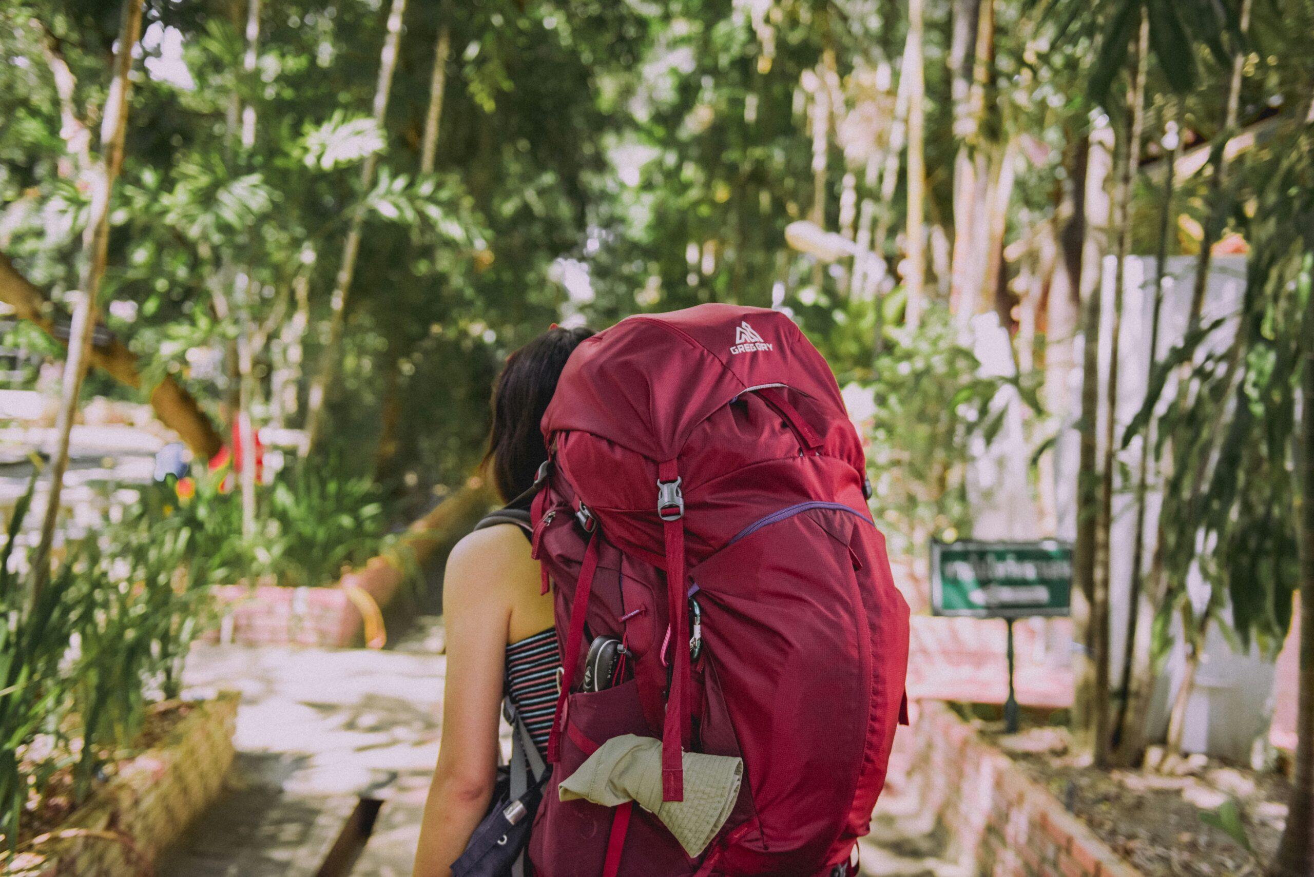 Woman carrying a heavy backpack representing the cost of wearing your armour and carrying protective patterns through life.